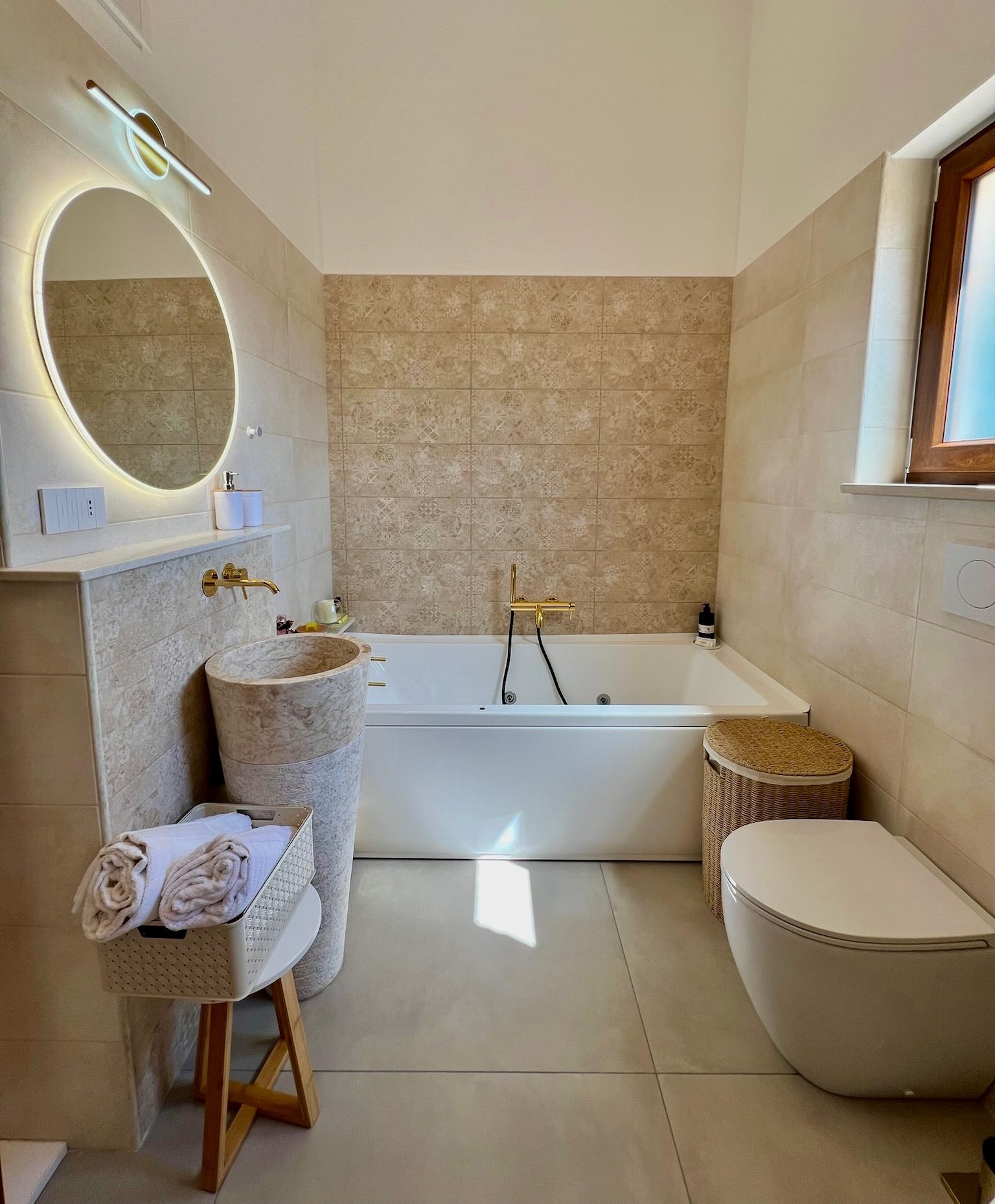 Bagno privato con vasca e lavabo monolitico in pietra
